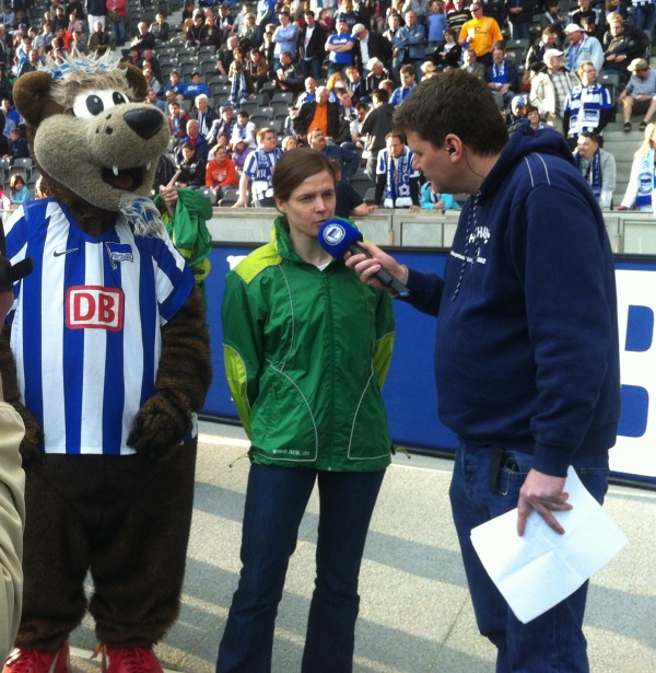 Interview im Olympiastadion. Herthinho links und der Stadionsprecher rechts von mir. Ich in einer gr&uuml;nen AOK Outdoor Jacke, Foto: gute-presse.de