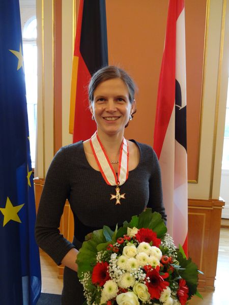 Ich mit dem Verdienstorden und einem wunderbaren Blumenstrau&szlig; vor den Flaggen Berlins, Deutschland und der EU